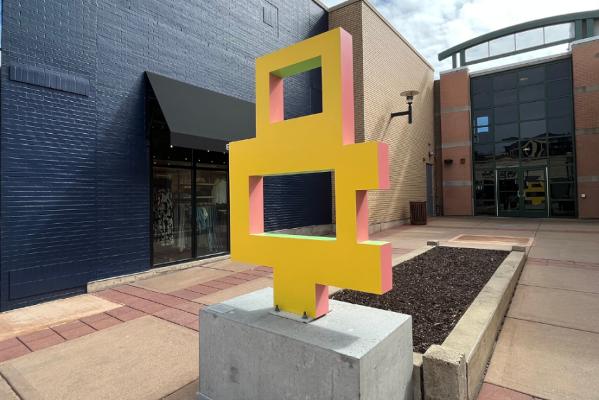 abstract yellow sculpture on gray concrete base